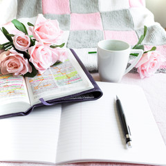 Pink Bible flat lay: Bouquet of pink roses, open Bible, black tea, coffee, journal, notebook, pen and pink blankets. Morning devotional. Rose, white, grey tones. Baselland, Switzerland - 02.04.2020