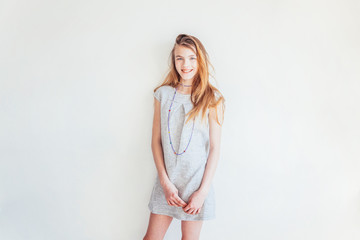 Happy teenage girl smiling. Closeup portrait young happy positive teen woman in grey dress against white wall background. European woman. Positive human emotion facial expression body language.