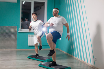 Fat man is very hardworking doing step-up exercises on steps during group fitness classes. Excess weight