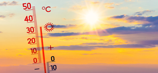 Thermometer against the background of the evening sky with bright sun shows 35 degrees heat, summer heat