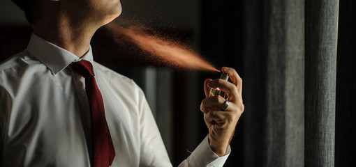 man spraying perfume with back light