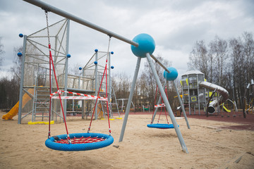 Fototapeta premium The playground in the city park is fenced with warning tapes in red and white. Coronavirus pandemic covide 19 worldwide. Self-isolation and measures to prevent the spread of the virus.