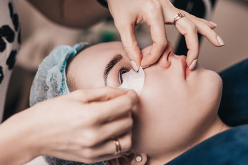 Preparation for eyelash extension procedure - the master sticks a patch on the lower eyelid