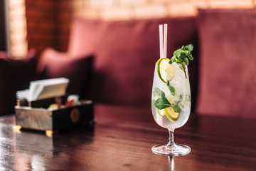 Mojito cocktail with lime mint and ice side view. Refreshing drink with a straw