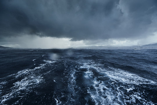 The view of the stormy sea and mountains from the sailboat, Path from foam after the boat, splashes from under the boat, rainy weather, dramatic sky © Vladimir Drozdin