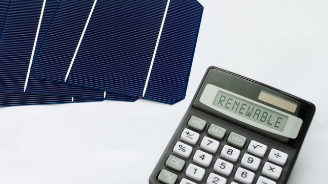 Solar energy cells with calculator showing the word Renewable in a conceptual image for sustainable energy sources