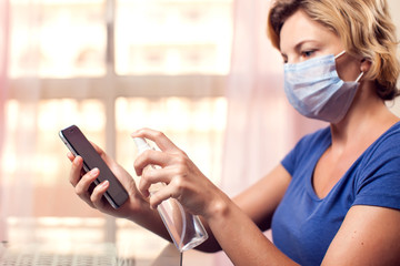 Woman cleaning smartphone with antiseptic. Hygiene concept