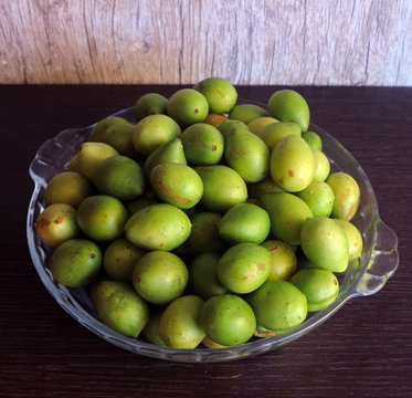 
glass bowl filled with umbu fruit on a dark wooden background