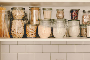 Kitchen storage organization. Zero waste, plastic free. Pasta, grains in glass jars. Organic food. Home cooking. Pantry food cabinet. Nutrition food. Glass containers. Food preparation. Stay home.