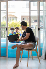 A father is working while he watches his sons swim in a small pool in house.