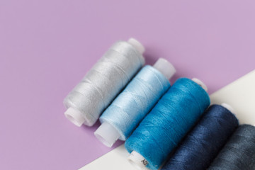 close-up of colored thread for sewing on a lilac background with a place for the inscription. the view from the top