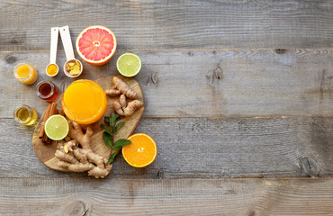 Top view on the immune system booster - orange juice, ginger, turmeric, citruses, and honey on the old wooden table