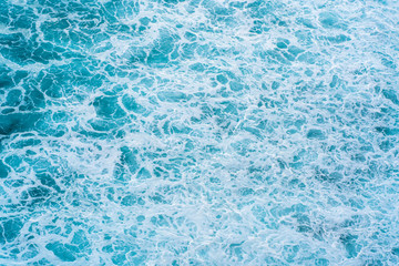 Texture Light blue surface of raging sea water with white foam and wave pattern.The azure surface of the ocean. Aerial photography of water. Azure sea natural background.