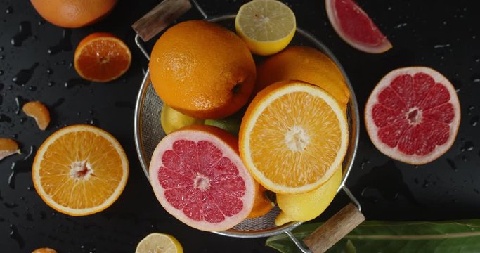 Colander with slices of different citrus slowly rotates.