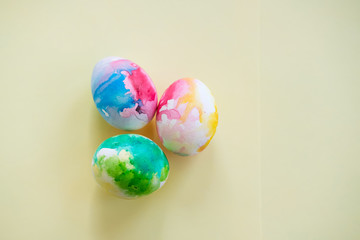 Colorful Easter eggs in watercolor style on a yellow background close-up. Easter concert. Bright colorful spots. The view from the top or flat lay