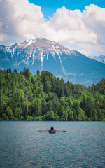 Tourists enjoying beautiful views from the Bled lake while sitting in their canoe