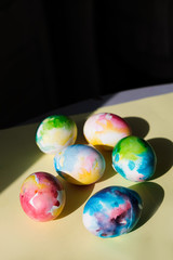Colorful Easter eggs in watercolor style on a yellow background close-up. Easter concert. Bright colorful spots. Bright sunlight, direct rays of the sun.