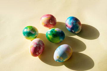 Colorful Easter eggs in watercolor style on a yellow background close-up. Easter concert. Bright colorful spots. The view from the top or flat lay