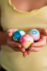 Colorful Easter eggs in watercolor style in the hands of a girl close-up. Easter concert.