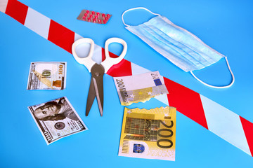Cut money dollars and euros on a blue background. The concept of problems in the global financial...