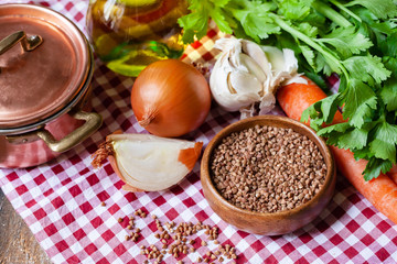 Dry uncooked buckwheat in wooden bowl for traditional russian meal. Can we served with fried mushrooms and vegetables. Healthy food, low calories, easy to cook. Copper pan, wooden backround, close up