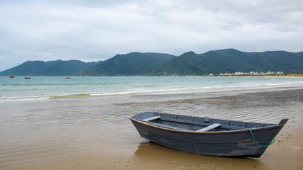 Fototapeta na wymiar Barco de pescador e a costa verde montanhosa das praias de Açores e da Solidão, Florianópolis - SC, Brasil