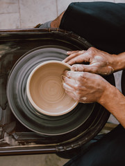 Potter at work Top view photo Man is sculpting a bowl behind a rotating potter's wheel
