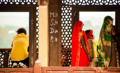 women, model, in gorgeous orange dress looks at the horizon from a window of the ruins of a religious temple in India