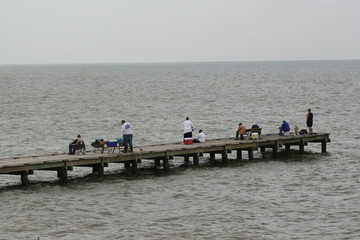 Fototapeta na wymiar Fishermen fishing off of pier in gulf of mexico