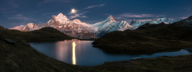 Bachalpsee lake with moon over mountains, scenic night landscape, Swiss Alps, Switzerland.