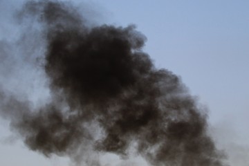 Thick black smoke in the clear sky