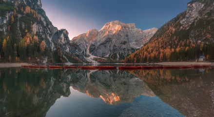 Lago di Braies scenic autumn panorama. Beautiful lake with boats and mountains reflection. Pragser Wildsee, South Tyrol, Italy