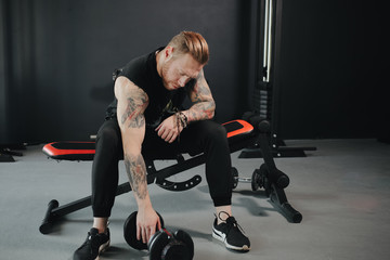 fitness trainer lifts dumbbells with emphasis on a bench in the gym