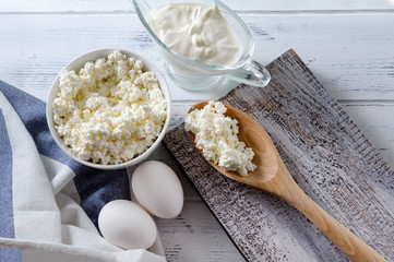 protein products , cottage cheese, sour cream, white eggs, towel on a white wooden background, dairy,
