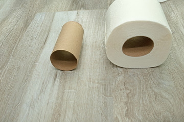 toilet paper on the floor made of ceramic tiles. New and used rolls of white toilet paper.