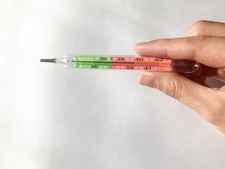 female hand holds a thermometer. thermometer shows heat, high temperature