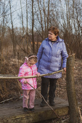 Grandmother and granddaughter walk along a country road. A little girl and an adult woman walk together.