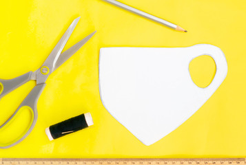 Making a medical facial mask at home with a sewing kit, black mask on a yellow background, layout...