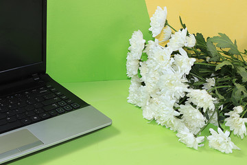 Greeting card Happy Mother's Day, computer and flowers on a light table, remote work, minimal spring concept. Stylish modern home office, comfortable workplace,