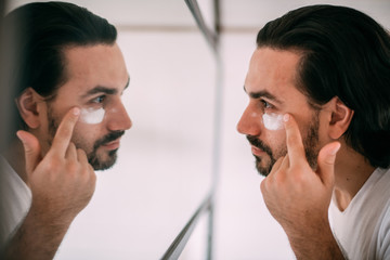 Handsome man smears face cream. Men's personal care