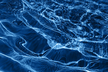 Closeup of rough water surface texture with splashes and bubbles in dark blue color. Trendy fresh abstract nature background. 2020 color concept