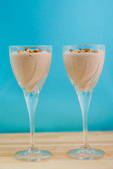 Two glasses with a banana smoothie of chocolate and ice cream on a blue background.