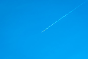 Jet Plane Crossing Through the Blue Sky Leaving a White Path Behind