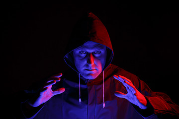 A man in a protective suit in a dark room. Halloween image concept. Virus protection. Illuminated with colored lights