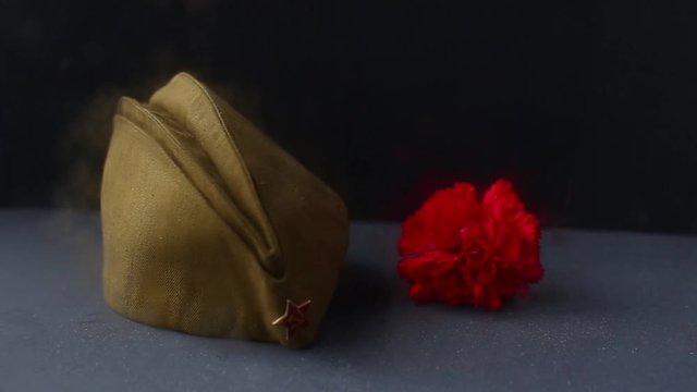 Forage, garisson cap of World War II soldier with red star,carnation flower, St. George ribbon. Memory of 75 years of victory day on May 9 of the Soviet Union in Great Patriotic War. Dark background