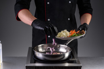 the process of cooking noodles with meat and vegetables in the restaurant kitchen