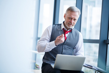 Adult male businessman, teacher, mentor working on a new project. Sits by a large window on the...