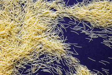 Dry pasta scattered on a black background close up with copy space. Food photo.