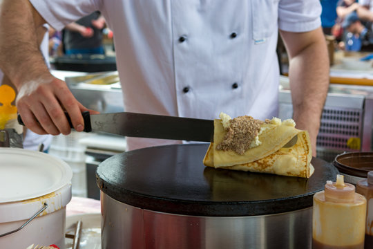Cheff preparing tasty pancake with wallnuts and cream.
