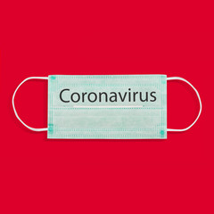 Medical face mask on a red background. The concept of a warning sign against the epidemic of the virus, coronovirus.